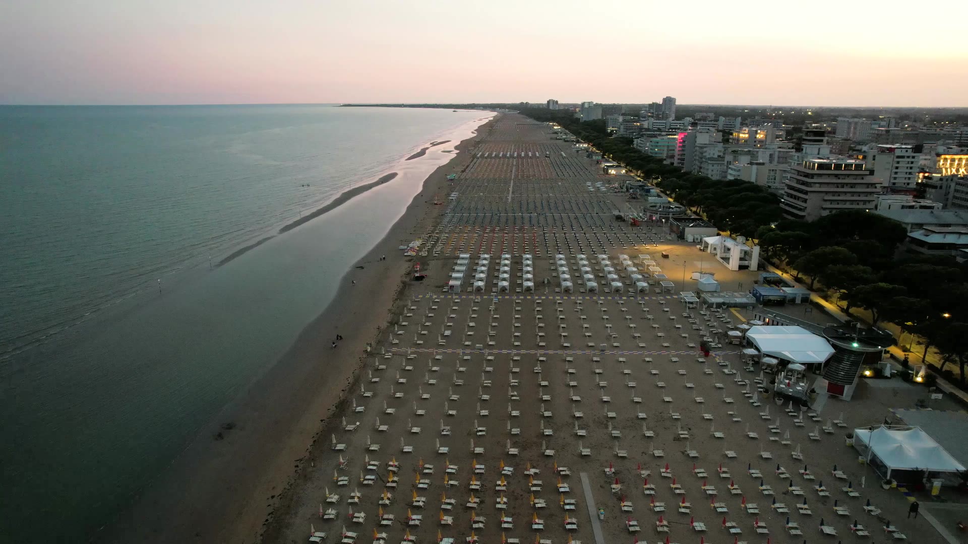 Lignano Sabbiadoro vista dall'alto al tramonto, file di ombrelloni lungo la spiaggia