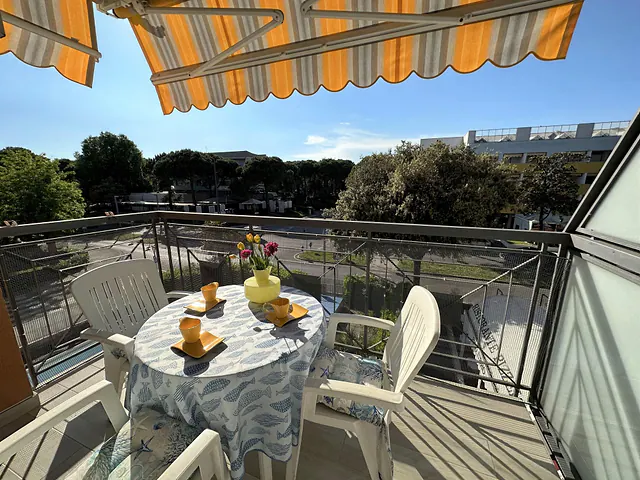 Balcone con tenda a righe e tavolo apparecchiato con vista sul verde