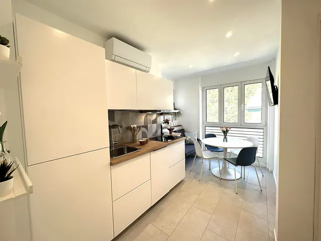 Cucina bianca con piano in legno e tavolo rotondo vicino alla finestra