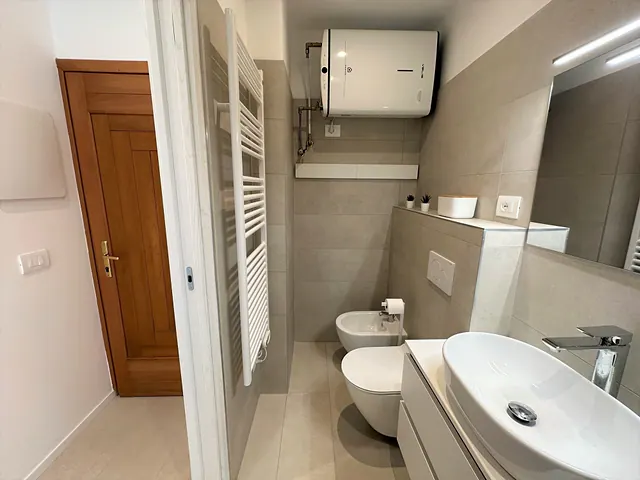 Bagno con sanitari sospesi, lavabo d'appoggio e scaldasalviette