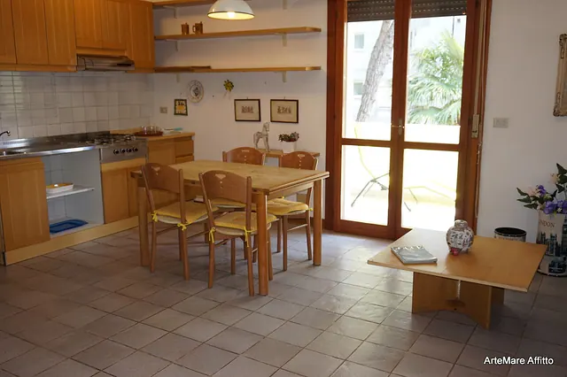 Soggiorno con cucina in legno, tavolo e portafinestra