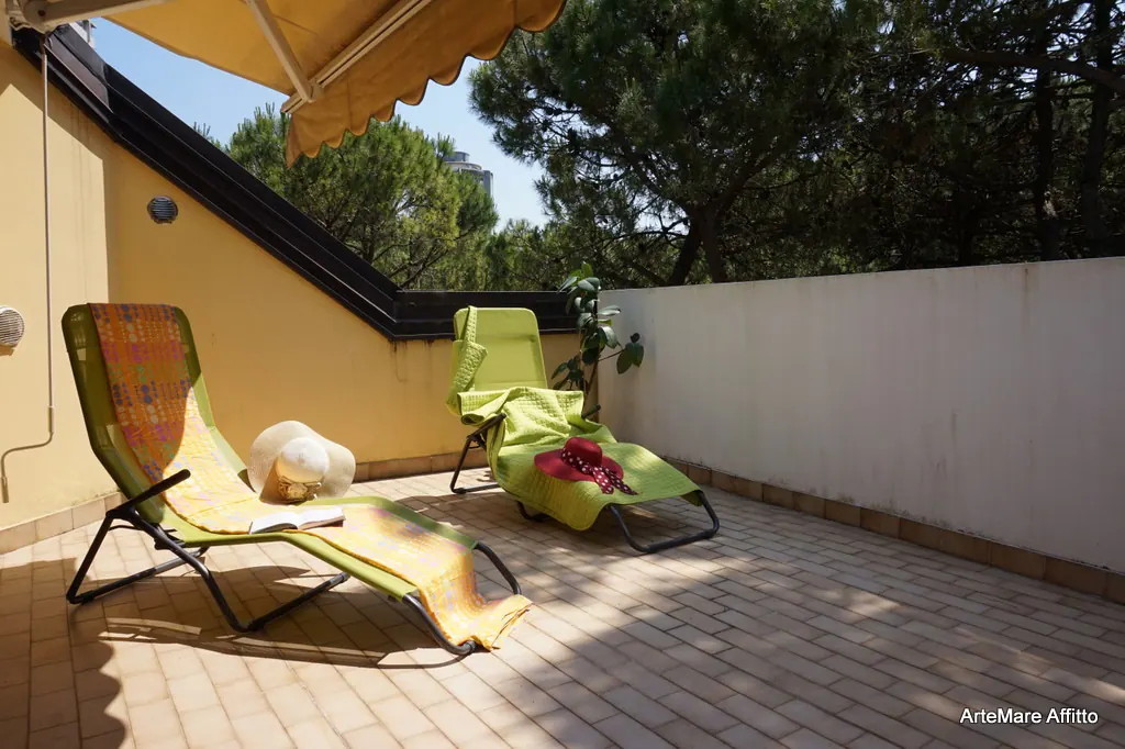 Grande terrazza con sdraio e pini marittimi