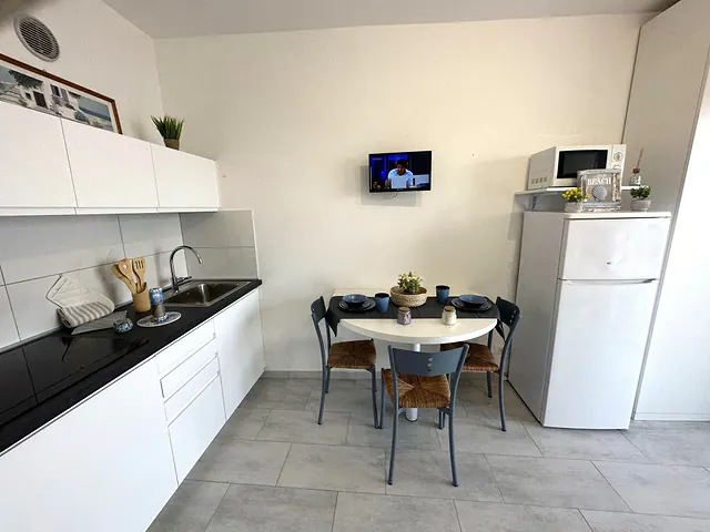 Cucina bianca con piano nero e tavolo rotondo