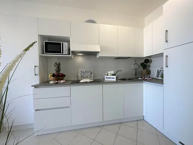 Cucina bianca ad angolo con microonde e decorazioni