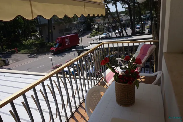 Balcone con tenda da sole, tavolino e fiori affacciato sul viale