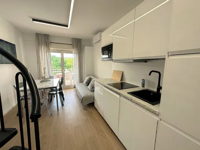 Cucina bianca moderna con piano a induzione e zona pranzo