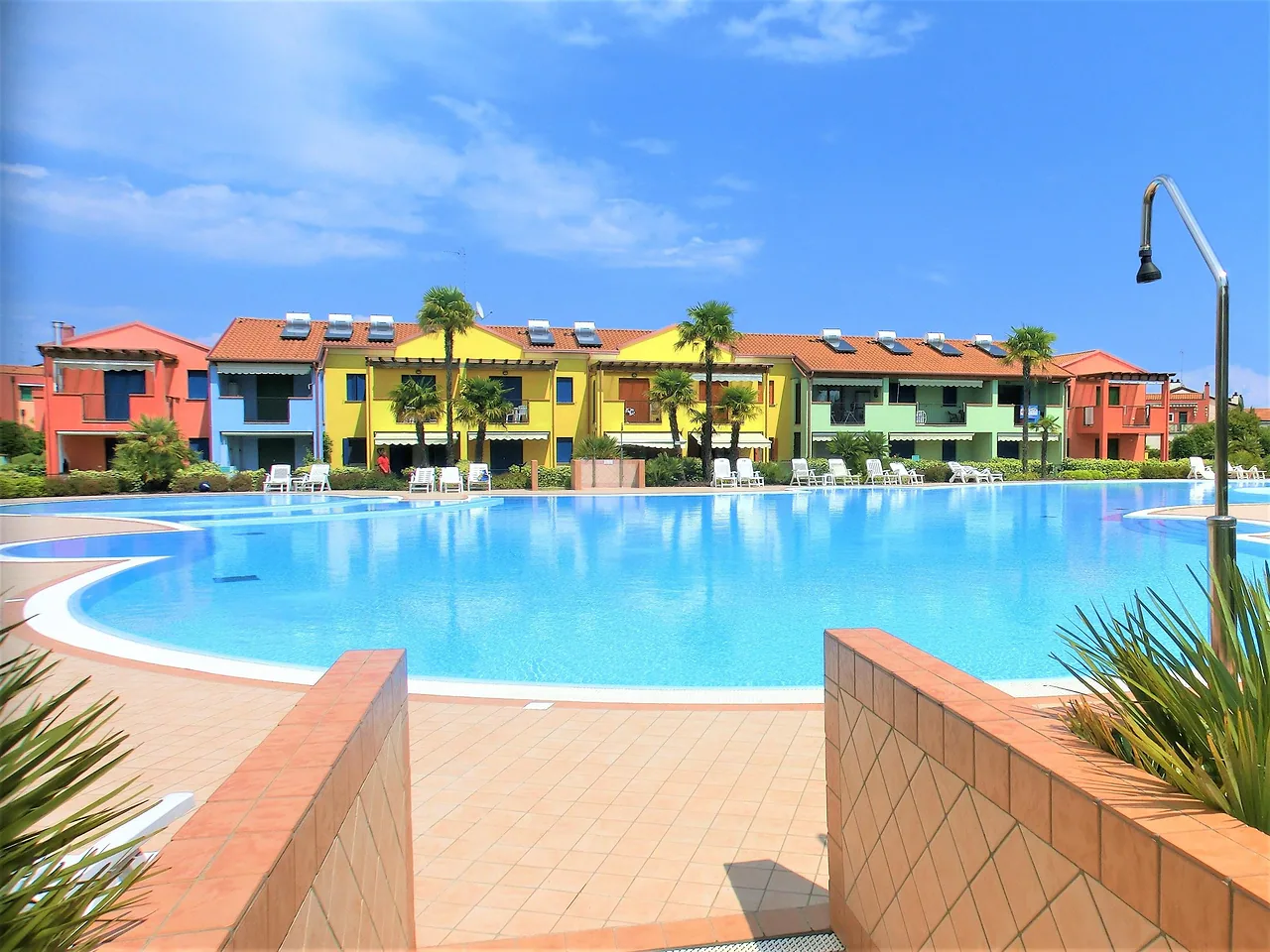 Grande piscina del Porto Antico Village con case colorate e cielo azzurro