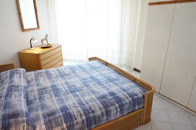 Camera matrimoniale con letto in vimini e comò