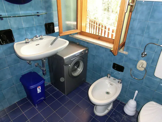 Bagno con piastrelle blu, lavatrice e sanitari