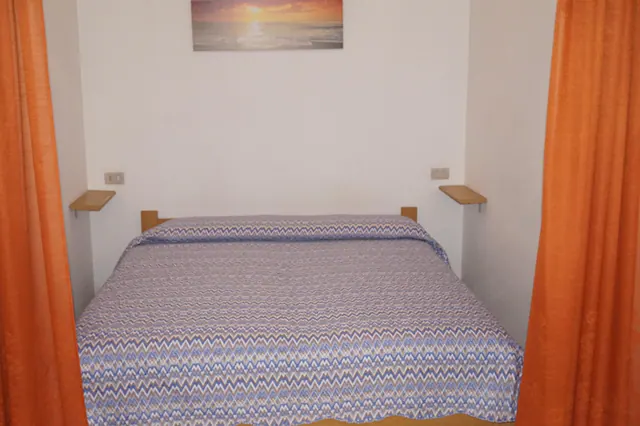 Nicchia notte con letto matrimoniale e tende arancioni