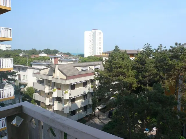 Vista dal balcone su pineta e palazzi con scorcio di mare