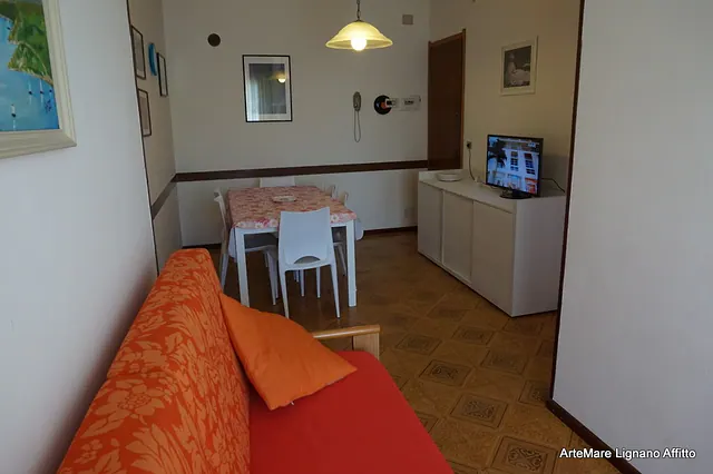 Soggiorno con divano arancione, tavolo da pranzo e TV