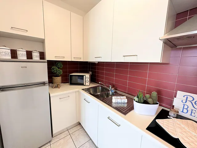Cucina bianca con rivestimento bordeaux e frigorifero