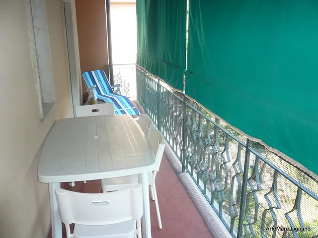 Terrazzo con tavolo, sdraio e tenda verde