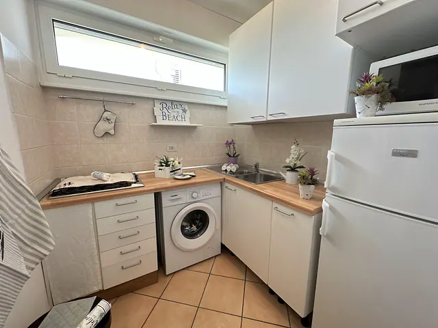 Cucina con lavatrice, frigorifero e piano in legno