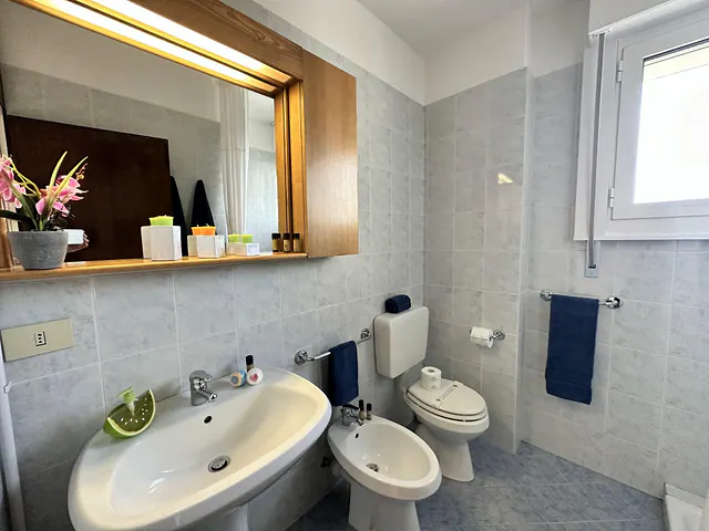 Bagno con specchio illuminato, lavabo e sanitari