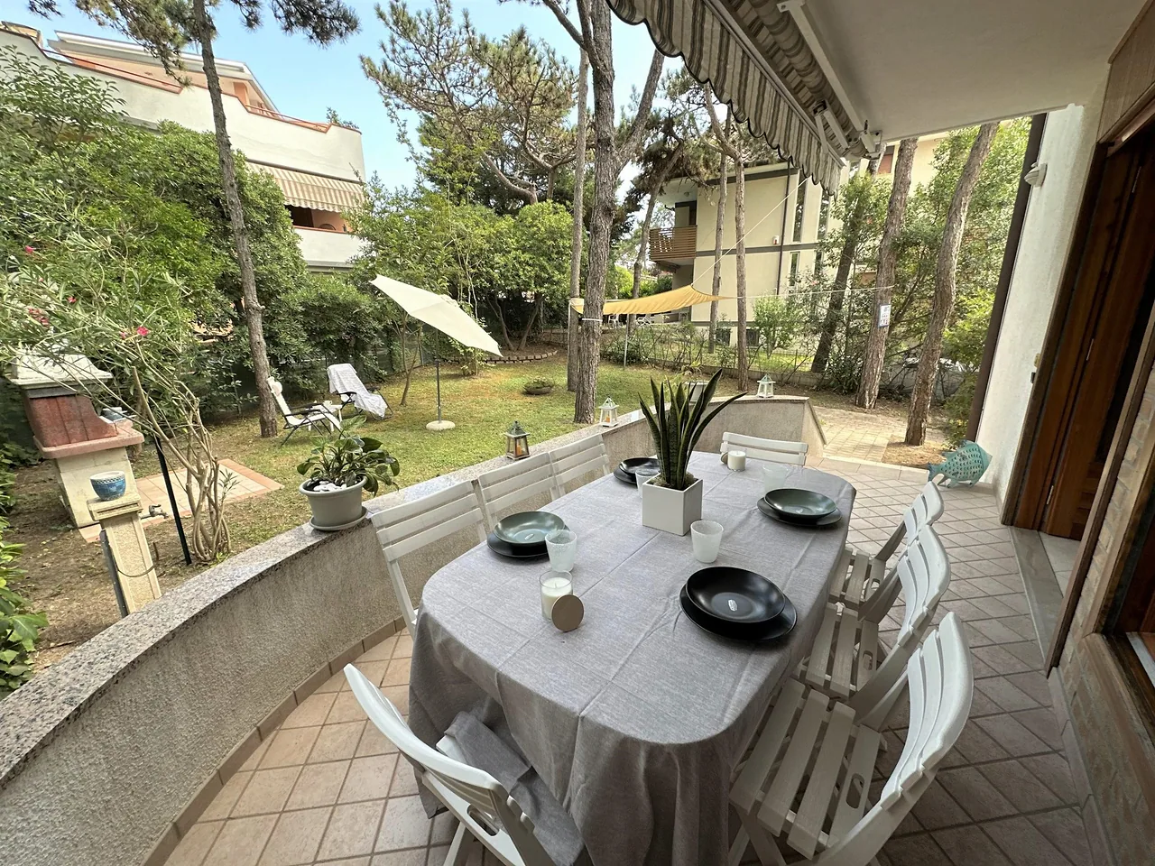 Terrazza con tavolo da pranzo affacciata sul giardino alberato