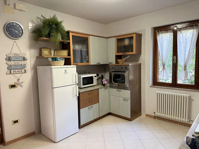 Cucina con frigorifero, forno e finestra