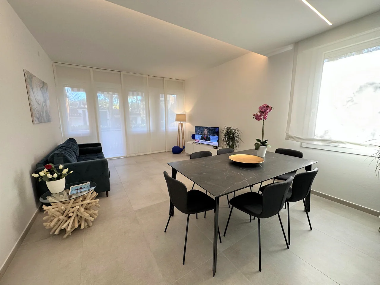 Living con tavolo in gres effetto marmo e divano blu