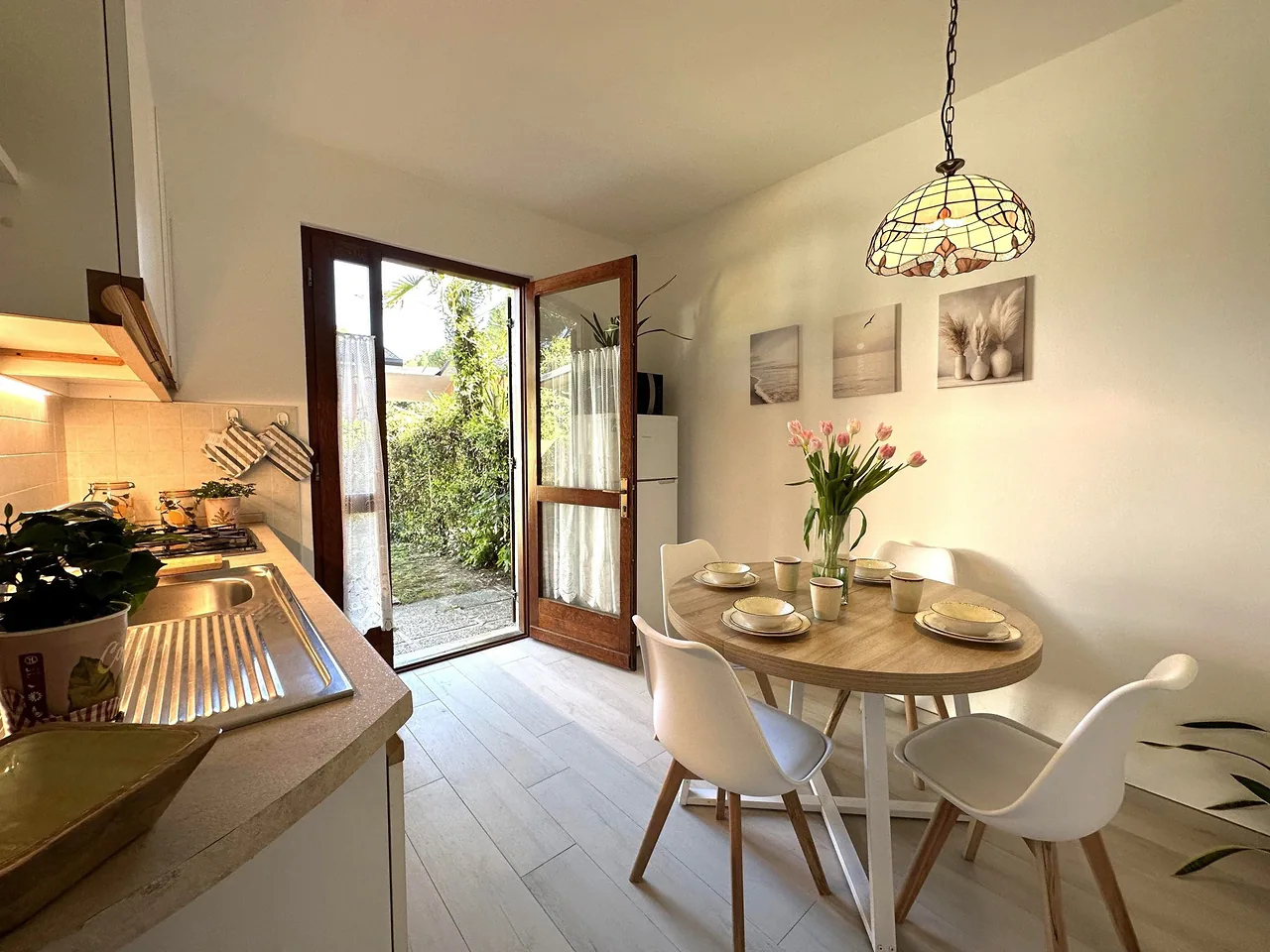 Cucina con tavolo rotondo apparecchiato e porta aperta sul giardino