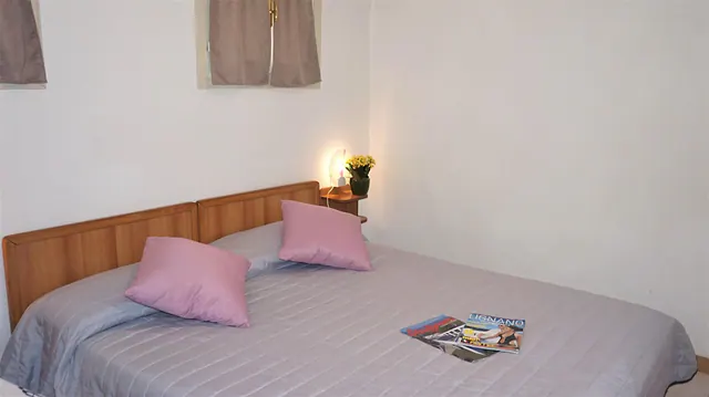 Camera matrimoniale con cuscini rosa e testiera in legno
