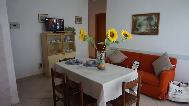 Soggiorno con tavolo apparecchiato, girasoli e divano arancione