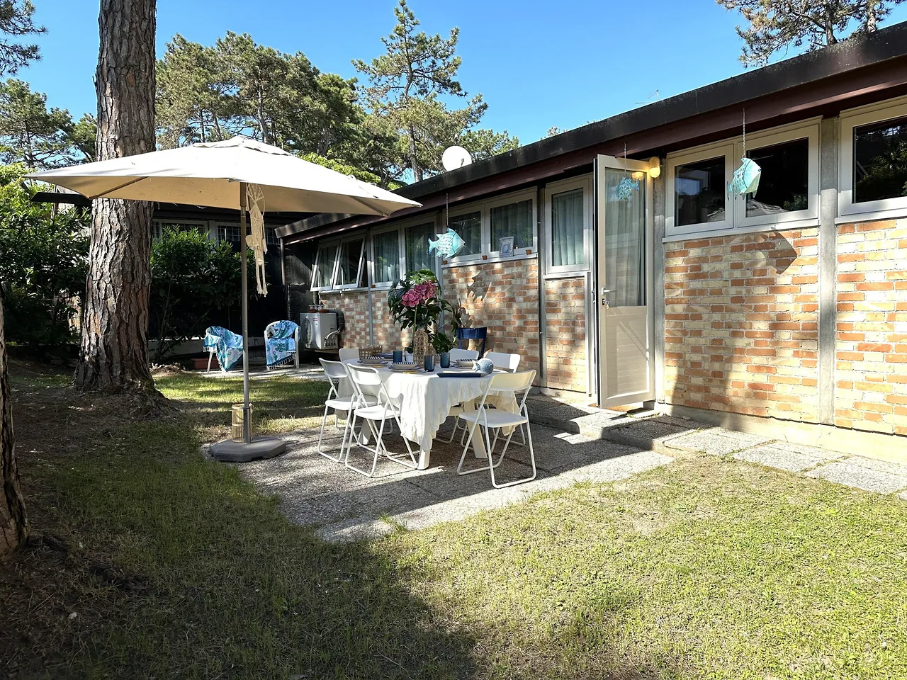 Patio con ombrellone e tavolo apparecchiato davanti alla villetta