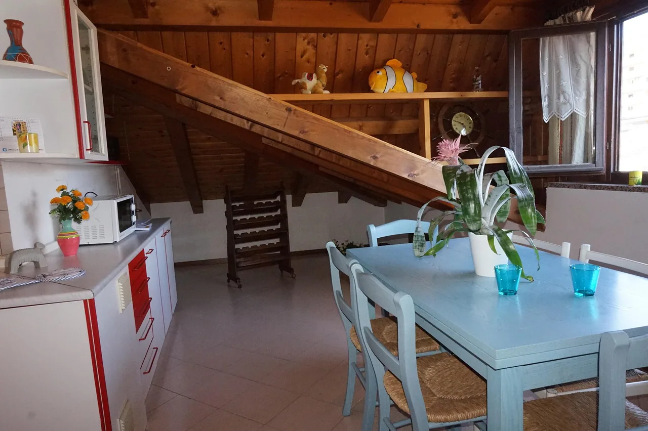 Soggiorno mansardato con travi a vista e tavolo apparecchiato