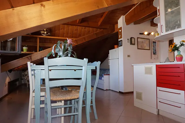 Zona pranzo con sedie azzurre e cucina