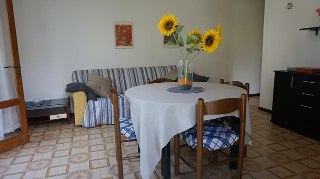 Soggiorno con tavolo rotondo, girasoli e divano a righe