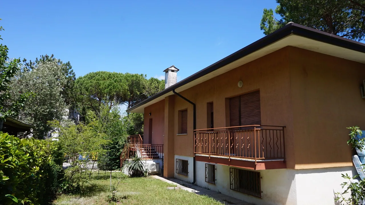 Villetta in mattoni con balcone e giardino sotto il cielo azzurro