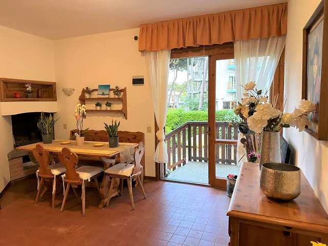 Zona pranzo con tavolo in legno e portafinestra sul giardino