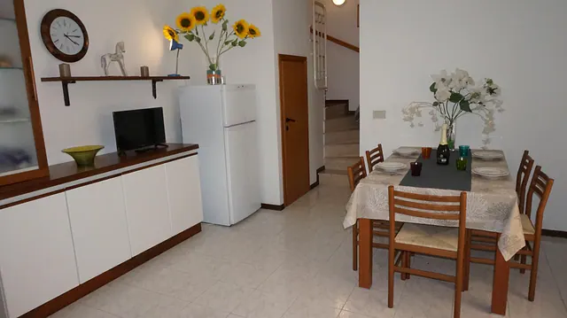 Soggiorno con tavolo apparecchiato, girasoli e frigorifero