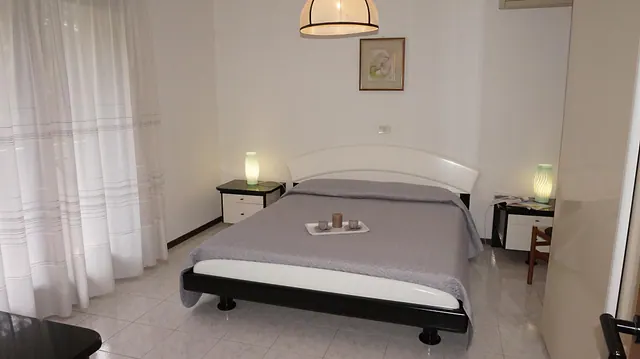 Camera matrimoniale con lampadario e tende bianche